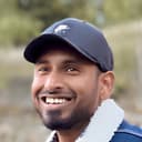 Snehan Chakravarthi, smiling, in a cap and denim jacket